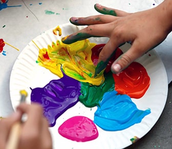 paper plate with finger paints and kid hands