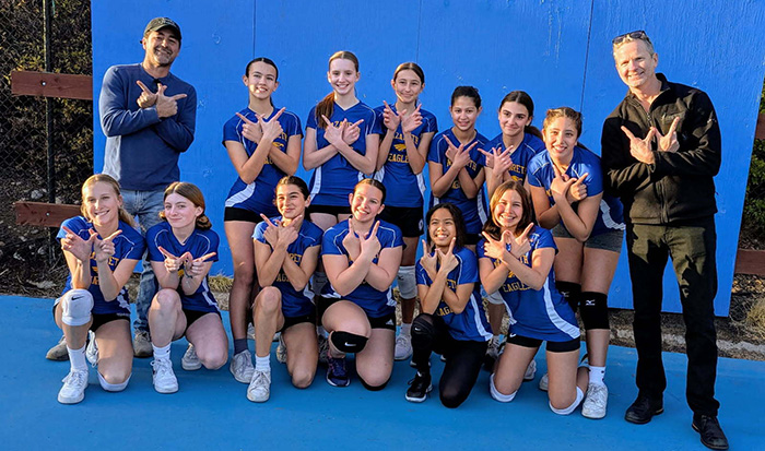 Girls athletic team in blue uniforms and their coaches
