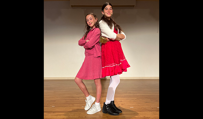 Two girl actors in red dresses on stage