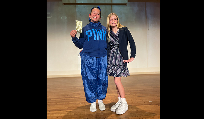 Two actors on stage holding up golden ticket