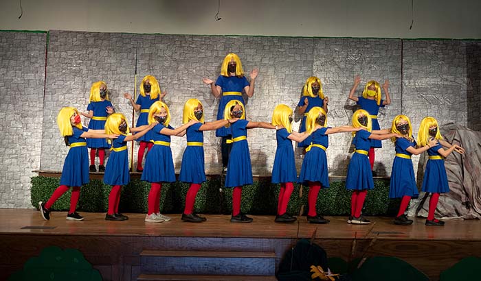 Dancers in matching blue dresses and yellow wigs
